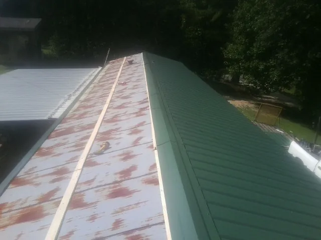Old rusted panels beside newly installed green metal roofing — Wind Damage Roof Repair by Roofing Brothers in Graceville