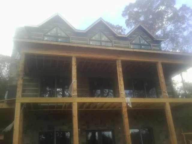 Dormers and porch framing on a large log home under construction — Roof Coating work by our crew in Graceville