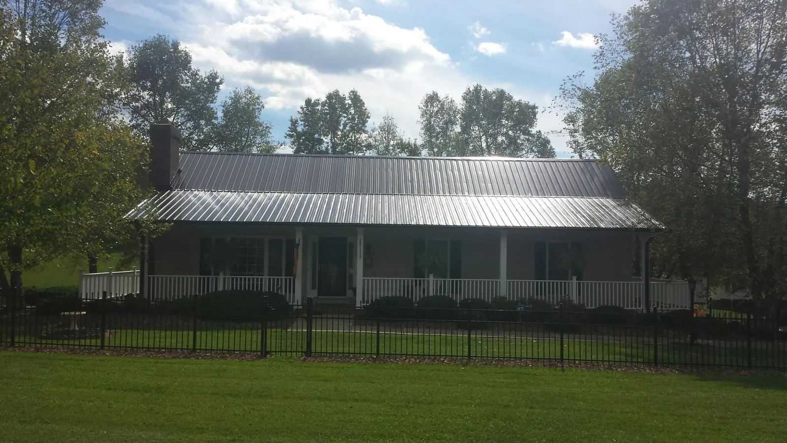 Gray metal roof on a brick ranch with a full width front porch — Gutter Guard Installation work by our crew in Graceville